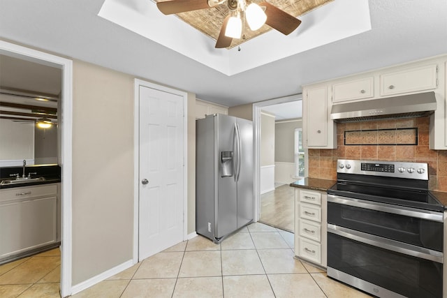 kitchen with light tile patterned floors, a tray ceiling, stainless steel appliances, and white cabinets