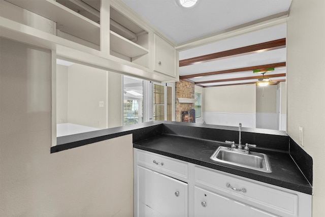 kitchen featuring white cabinetry, a stone fireplace, and sink