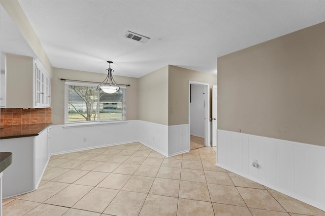 unfurnished dining area featuring a textured ceiling and light tile patterned floors