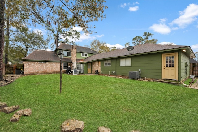 rear view of property with a yard and cooling unit