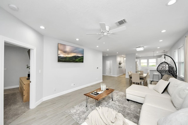 living room featuring a textured ceiling, light hardwood / wood-style flooring, and ceiling fan