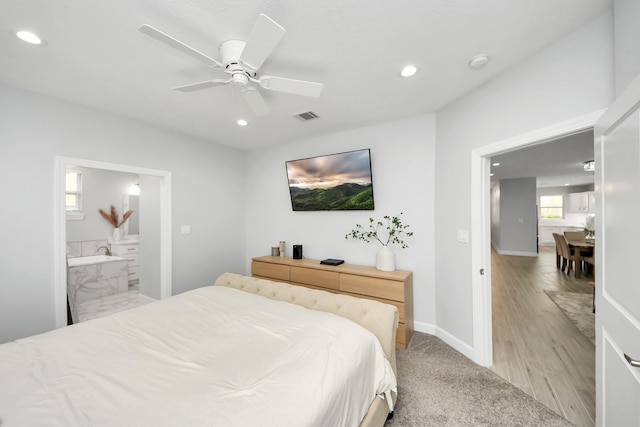 bedroom featuring ceiling fan, light wood-type flooring, and ensuite bath