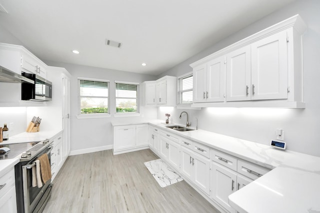 kitchen with light wood-type flooring, stainless steel appliances, sink, and white cabinets