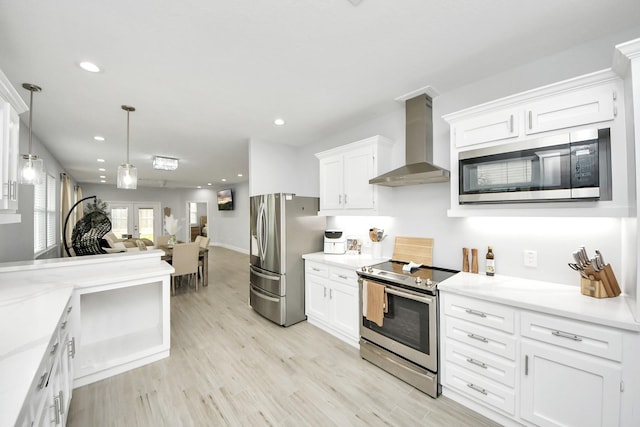 kitchen featuring appliances with stainless steel finishes, decorative light fixtures, white cabinets, and wall chimney exhaust hood