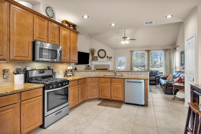 kitchen with lofted ceiling, sink, light tile patterned floors, stainless steel appliances, and backsplash