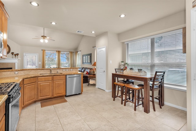 kitchen with a tile fireplace, vaulted ceiling, sink, ceiling fan, and stainless steel appliances