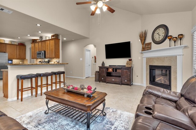 tiled living room with high vaulted ceiling, a tile fireplace, and ceiling fan