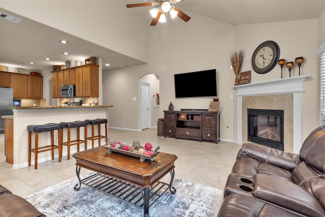 tiled living room with high vaulted ceiling, a tile fireplace, and ceiling fan