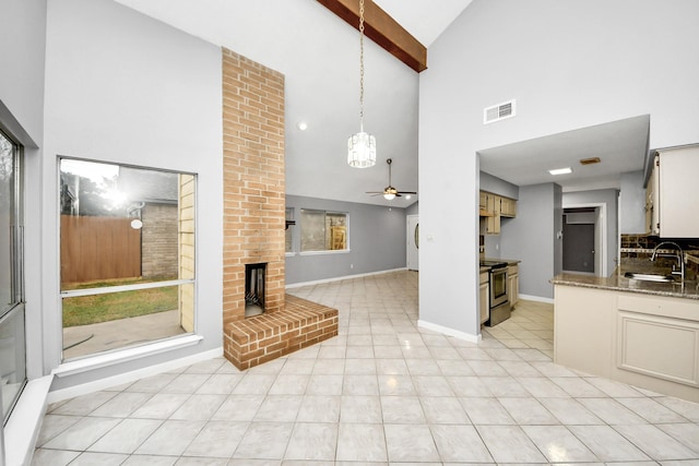 tiled living room with sink, beam ceiling, high vaulted ceiling, ceiling fan, and a fireplace