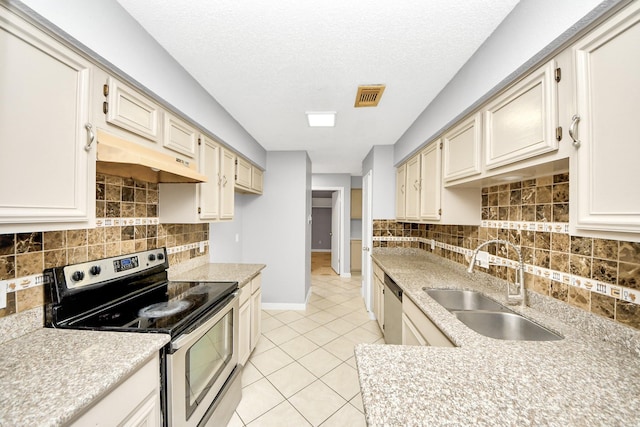 kitchen with sink, light tile patterned floors, stainless steel appliances, cream cabinets, and a textured ceiling