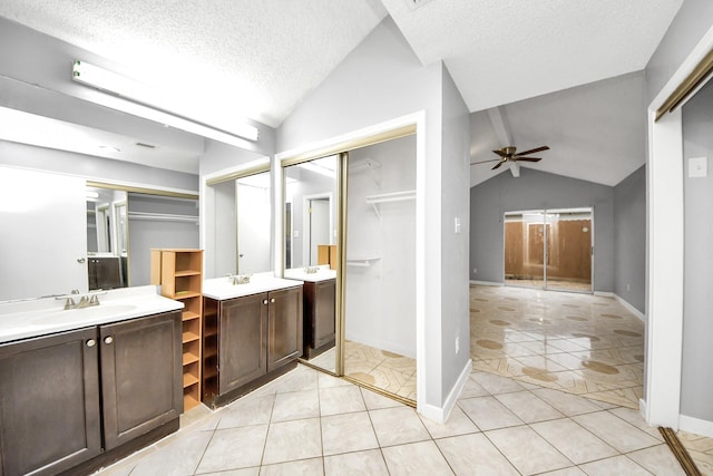 bathroom with lofted ceiling, ceiling fan, vanity, a textured ceiling, and tile patterned floors