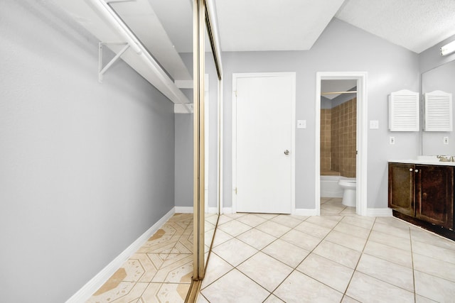 full bathroom featuring lofted ceiling, tiled shower / bath combo, vanity, toilet, and tile patterned floors