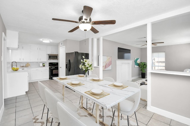 dining area with sink, a textured ceiling, and light tile patterned floors