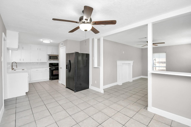 kitchen with sink, light tile patterned floors, black appliances, white cabinets, and a textured ceiling