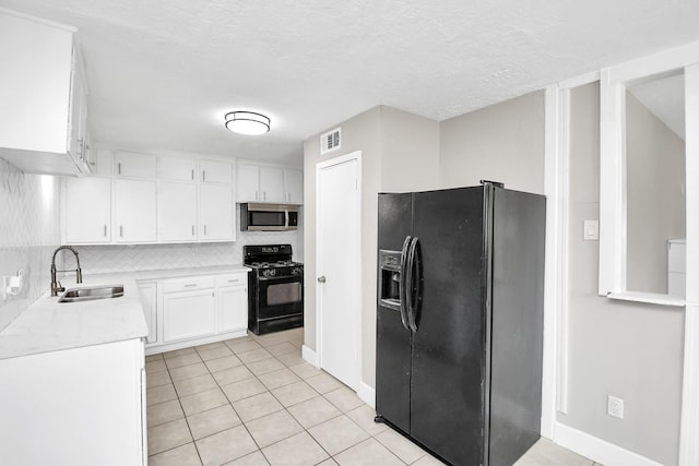 kitchen featuring light tile patterned flooring, tasteful backsplash, white cabinetry, sink, and black appliances