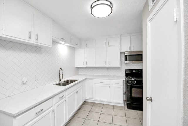 kitchen with black gas range oven, sink, white cabinets, and light tile patterned floors