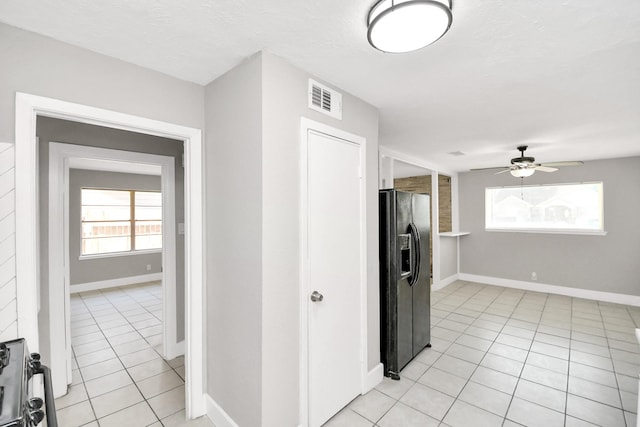 kitchen featuring light tile patterned flooring, black fridge, a textured ceiling, and ceiling fan