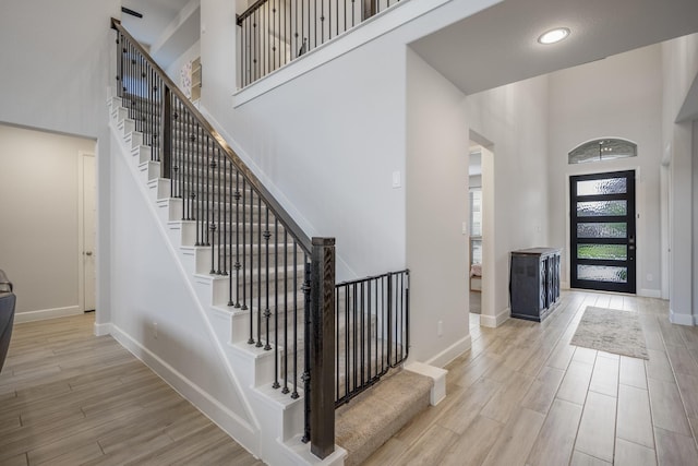 entrance foyer with a towering ceiling and light hardwood / wood-style flooring