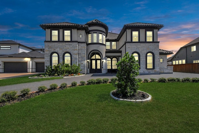 view of front of home featuring french doors, a garage, and a lawn