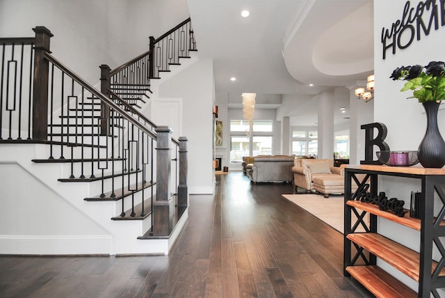 staircase featuring a towering ceiling, a chandelier, and hardwood / wood-style floors