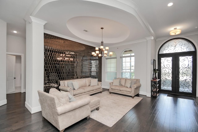 living room with a chandelier, a tray ceiling, crown molding, dark wood-type flooring, and french doors