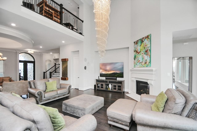 living room featuring a notable chandelier, a towering ceiling, dark hardwood / wood-style floors, and french doors