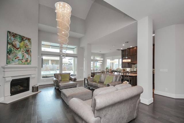 living room featuring an inviting chandelier, dark hardwood / wood-style floors, and a high ceiling