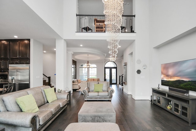 living room with dark wood-type flooring, an inviting chandelier, and a towering ceiling