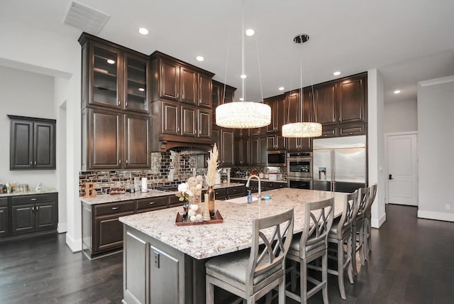 kitchen with sink, tasteful backsplash, hanging light fixtures, a center island with sink, and stainless steel appliances