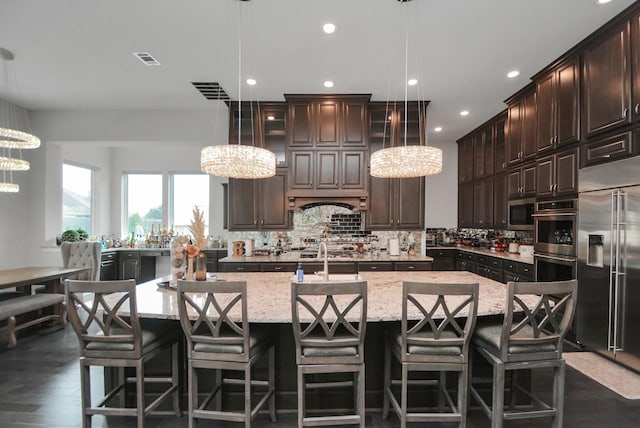 kitchen featuring hanging light fixtures, appliances with stainless steel finishes, and a center island with sink