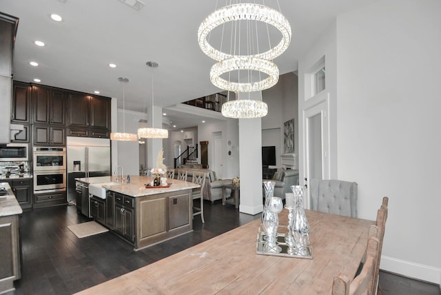 kitchen featuring appliances with stainless steel finishes, decorative light fixtures, sink, a kitchen island with sink, and an inviting chandelier