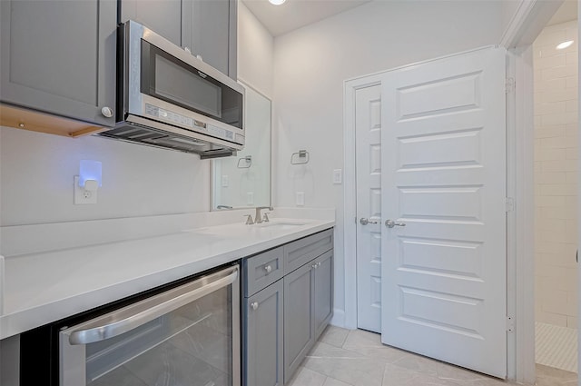 kitchen with gray cabinetry, sink, beverage cooler, and light tile patterned flooring