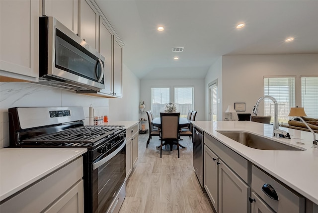 kitchen featuring gray cabinets, sink, decorative backsplash, stainless steel appliances, and light hardwood / wood-style flooring