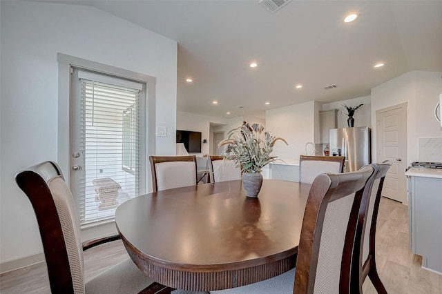 dining space with lofted ceiling, sink, and light hardwood / wood-style flooring