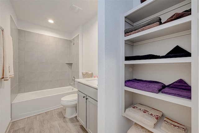 full bathroom featuring hardwood / wood-style flooring, vanity, toilet, and tiled shower / bath combo