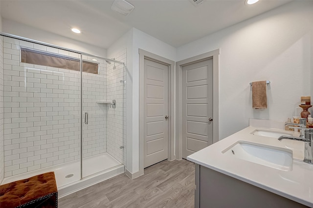 bathroom with wood-type flooring, vanity, and a shower with shower door