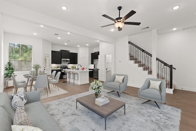 living room with hardwood / wood-style flooring, ceiling fan, and sink