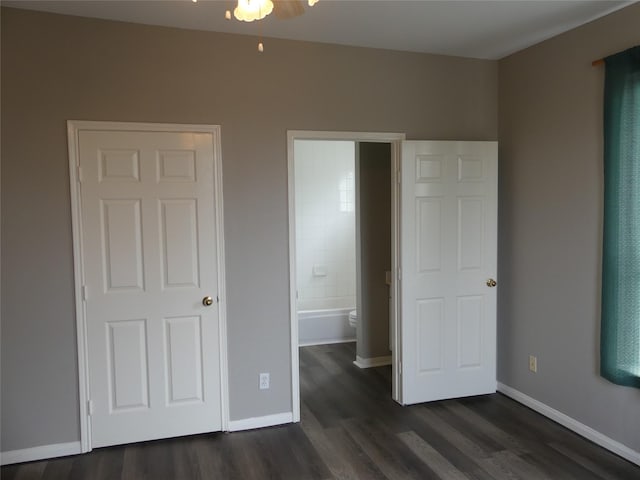 unfurnished bedroom featuring ensuite bathroom and dark hardwood / wood-style floors