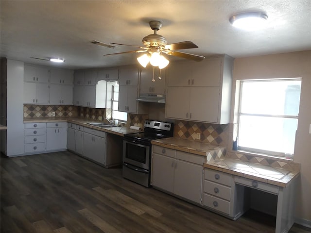 kitchen featuring dark hardwood / wood-style floors, sink, backsplash, tile counters, and electric stove