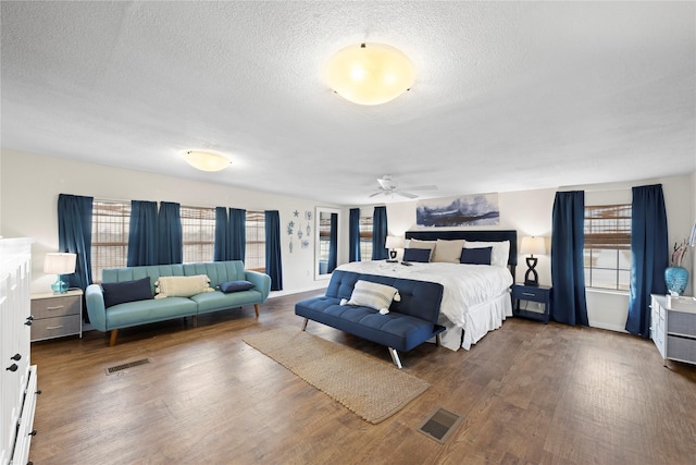 bedroom featuring multiple windows, dark hardwood / wood-style floors, and a textured ceiling