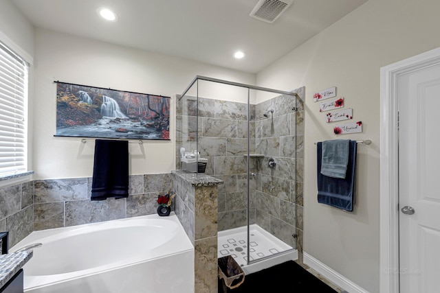 bathroom featuring plenty of natural light and separate shower and tub