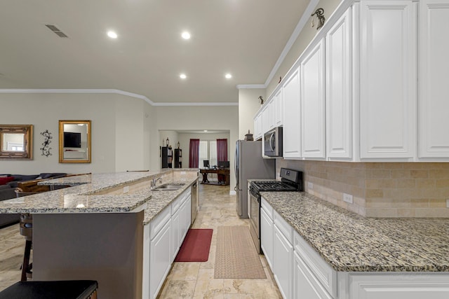 kitchen with light stone countertops, stainless steel appliances, white cabinets, and a spacious island