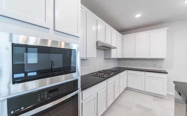 kitchen featuring dark countertops, under cabinet range hood, white cabinets, and stainless steel appliances