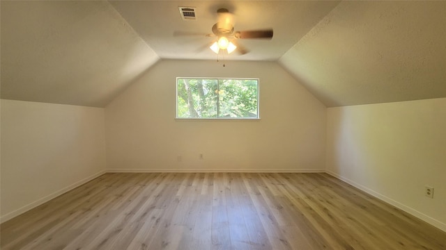 additional living space featuring vaulted ceiling, a textured ceiling, ceiling fan, and light hardwood / wood-style flooring