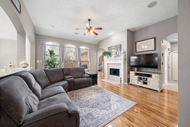 living room with hardwood / wood-style floors, a textured ceiling, a fireplace, and ceiling fan