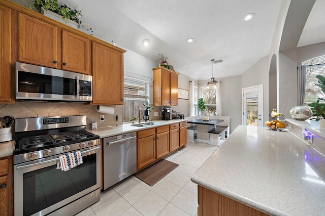 kitchen with vaulted ceiling, appliances with stainless steel finishes, decorative light fixtures, sink, and backsplash