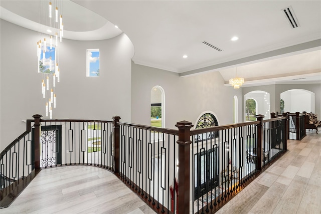 corridor featuring a wealth of natural light, a chandelier, and light hardwood / wood-style flooring