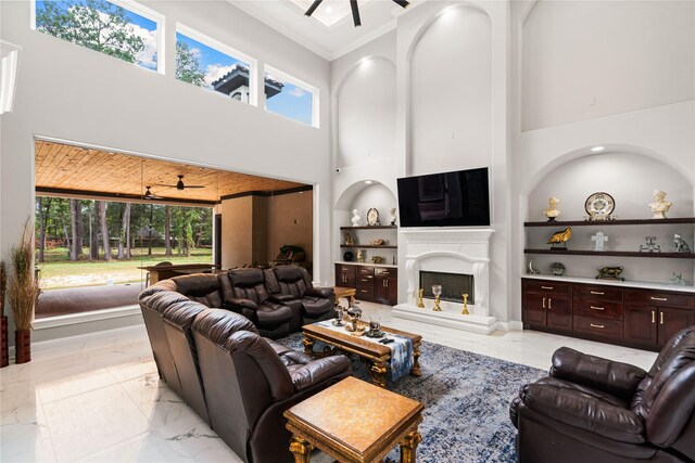 living room featuring crown molding, a healthy amount of sunlight, ceiling fan, and built in shelves