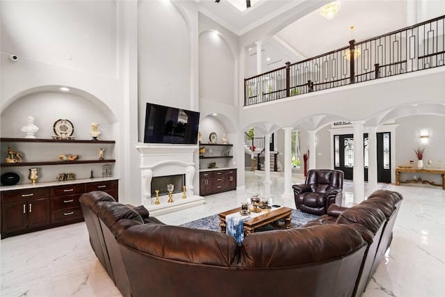 living room with decorative columns, ornamental molding, and built in shelves