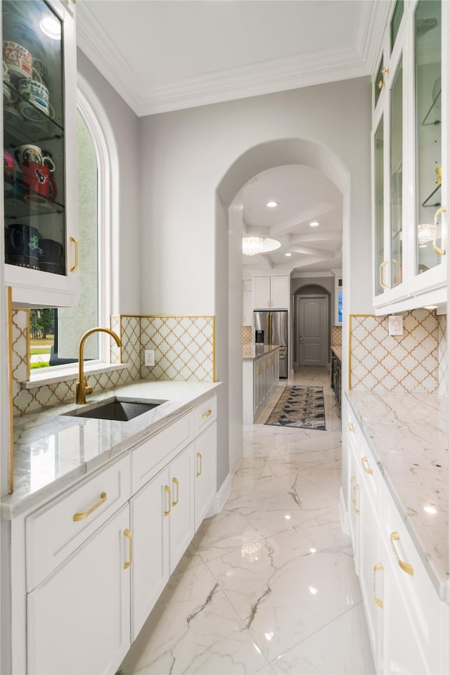 kitchen featuring light stone counters, sink, stainless steel fridge with ice dispenser, and white cabinets